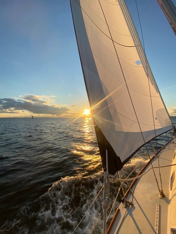 Custom roller furling genoa by Gleason Sailmakers on a Pearce 31 sailing at sunset – white genoa fully filled, golden light reflecting on the water with bow wave